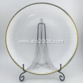 Clear glass plate dinner with gold rim.